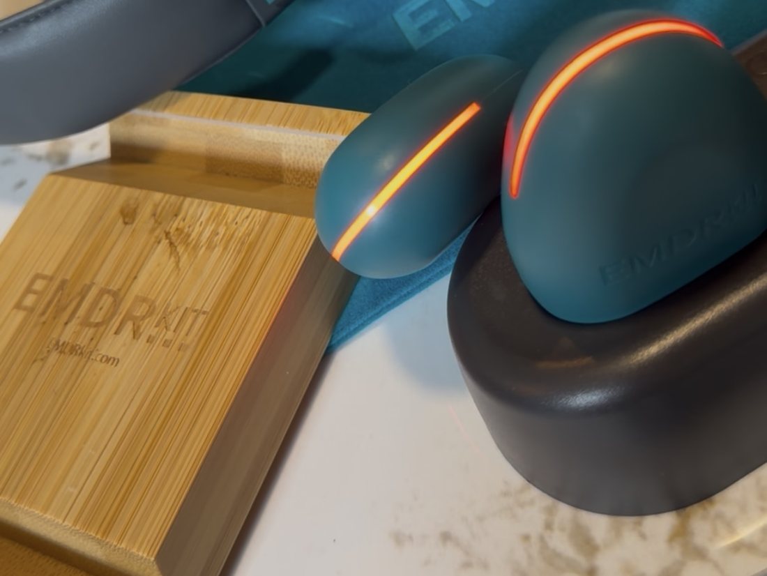 Deux buzzers EMDR vert-bleu avec leur bande lumineuse orange, sur leur base de recharge