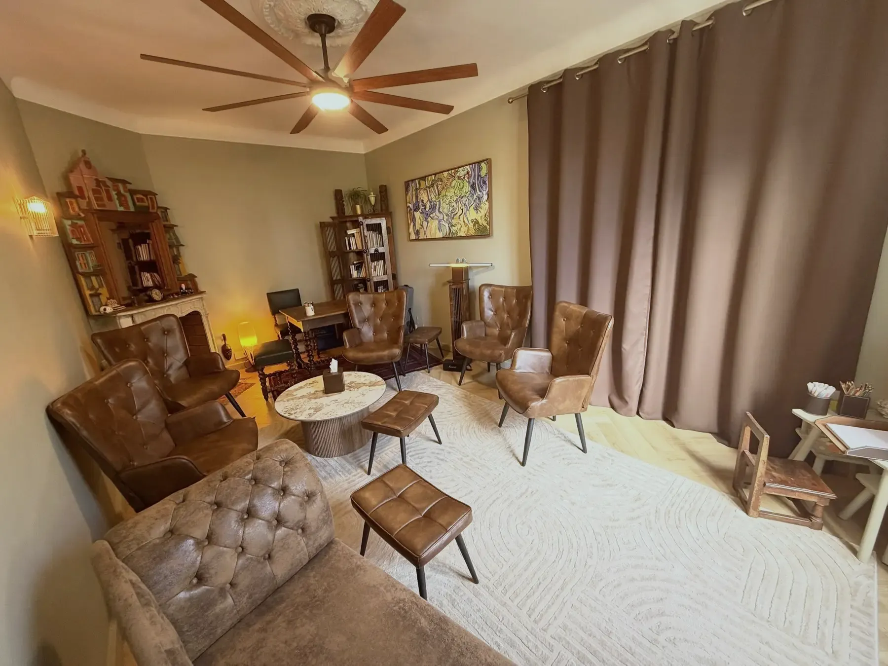 Salle de consultation du cabinet : fauteuils en cuir, divan, table basse, tableau et coin dédié aux enfants