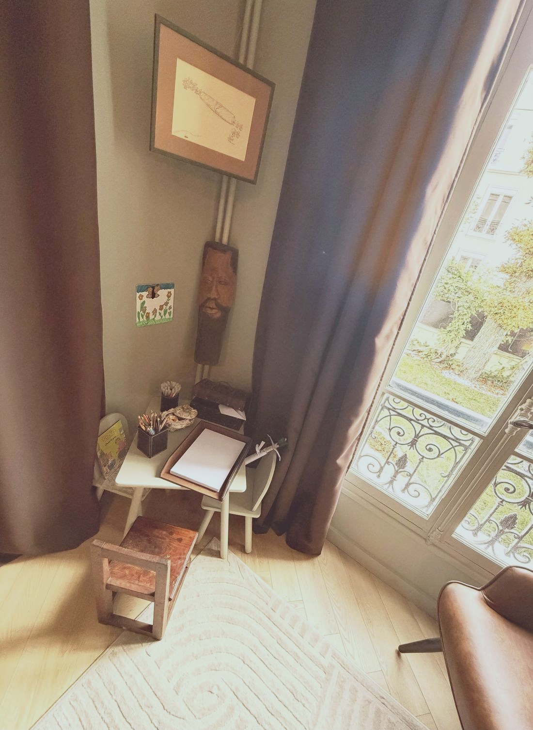Le coin dessin : petite table, crayons, feuilles et chaise d'enfant devant la fenêtre
